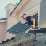 un artisan sur un toit installe un panneau solaire