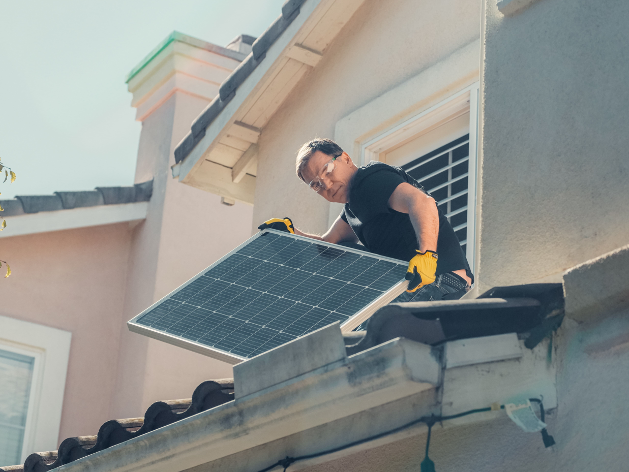 un artisan sur un toit installe un panneau solaire